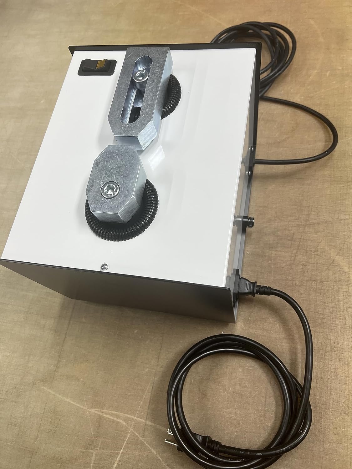 Metal device with attached power cord on table.